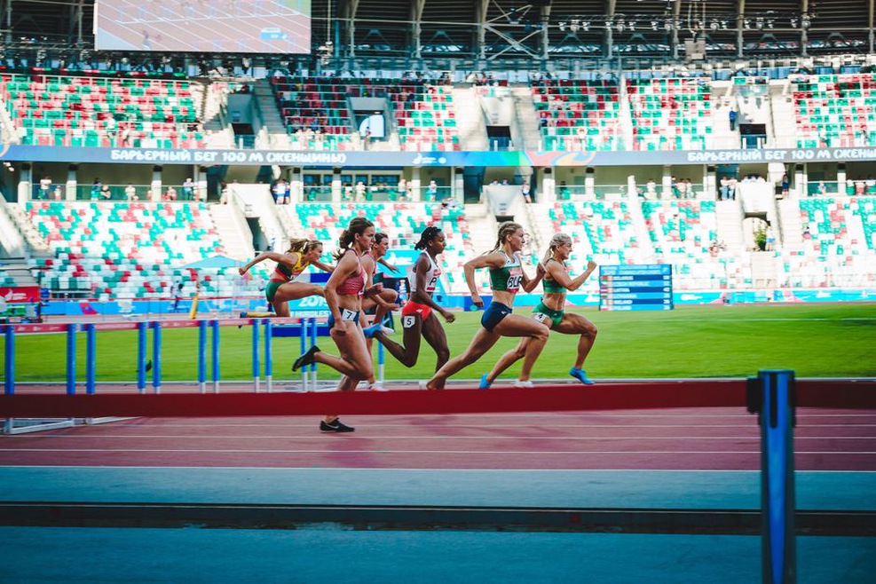 спортсменки проходят вираж легкоатлетической дорожки